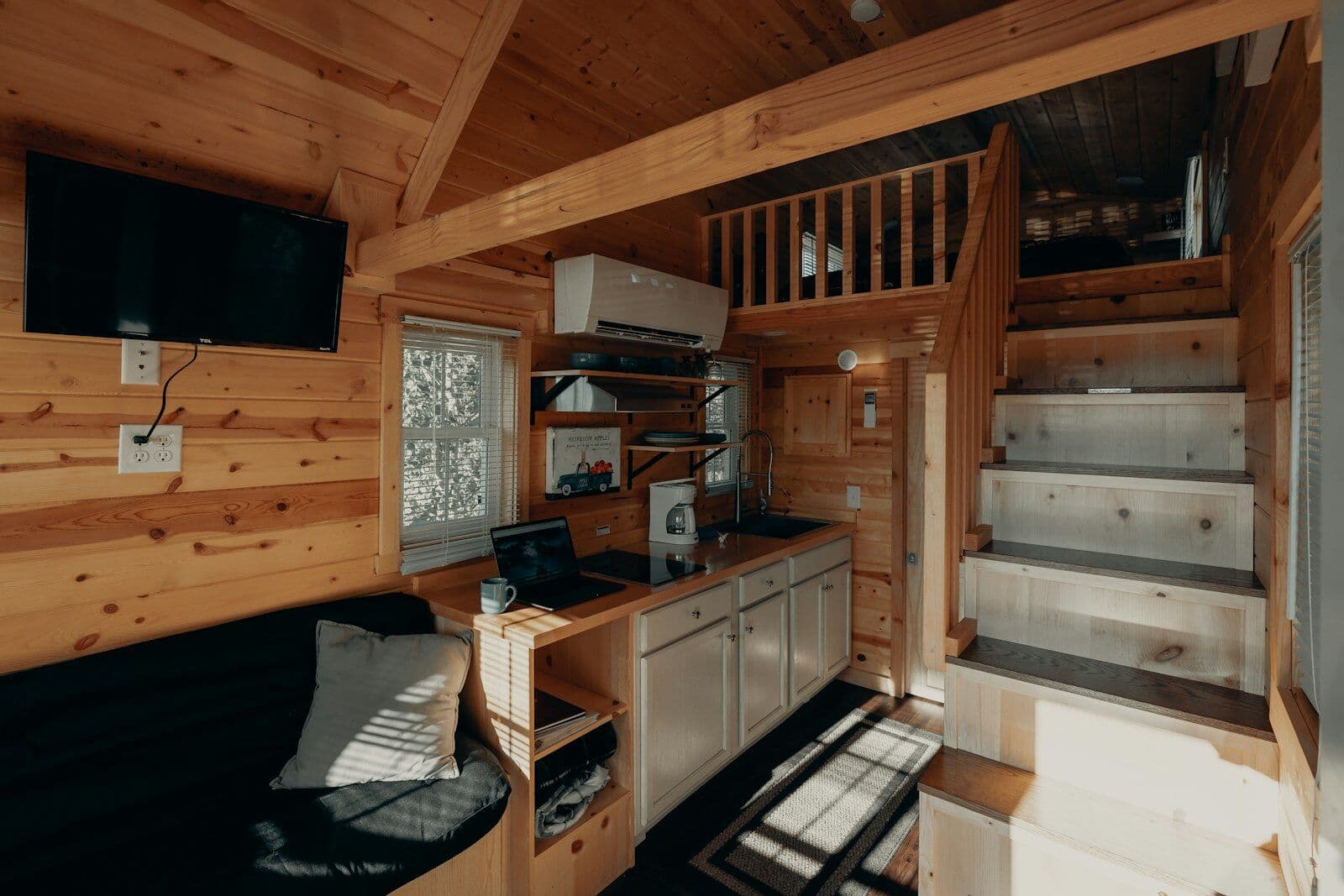 Kleiner Innenraum aus Holz mit Küchenzeile und Treppe zum Schlafboden