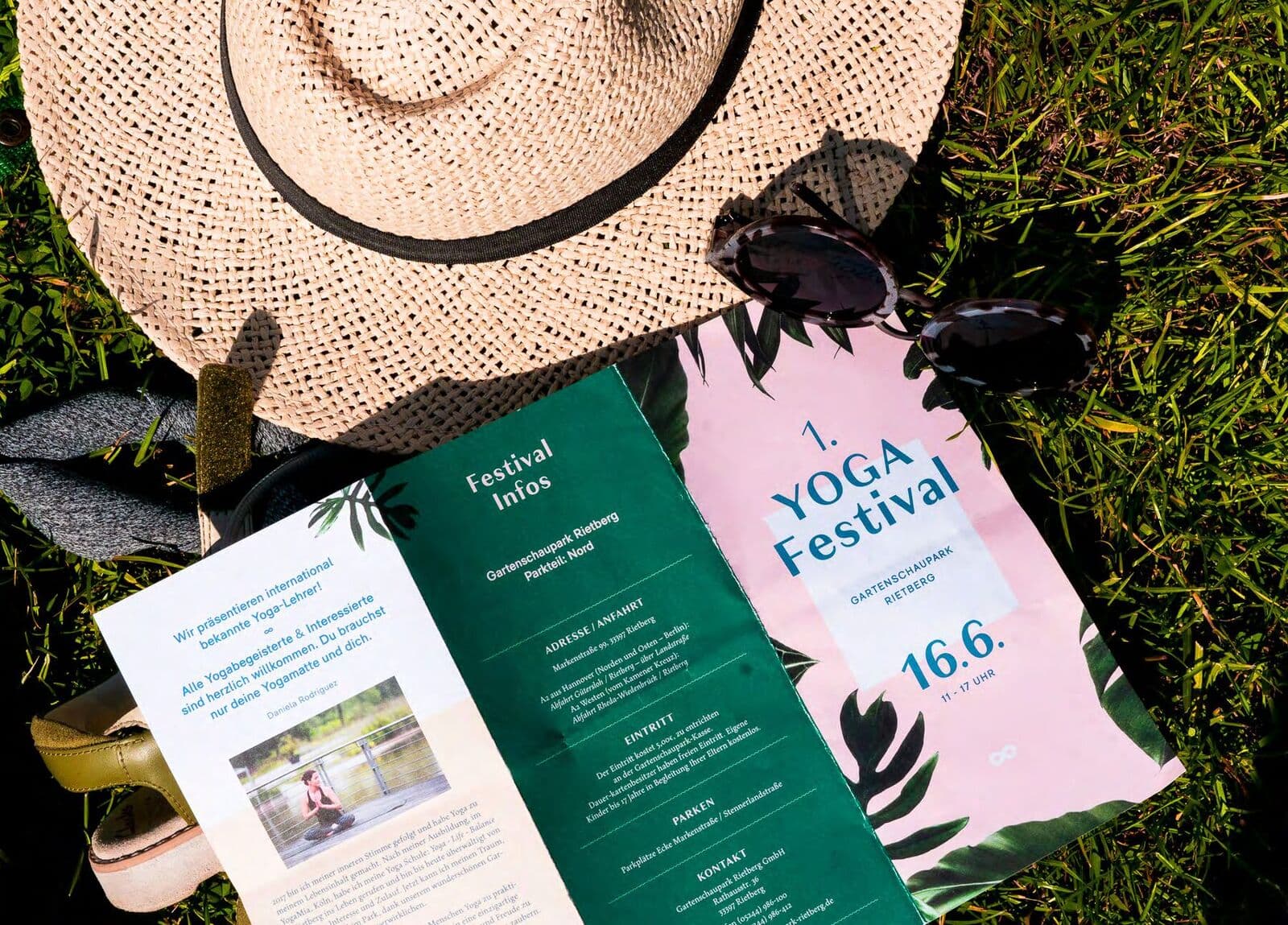 Strohhut, Sonnenbrille und Festival-Flyer in Grün und Rosa auf Gras